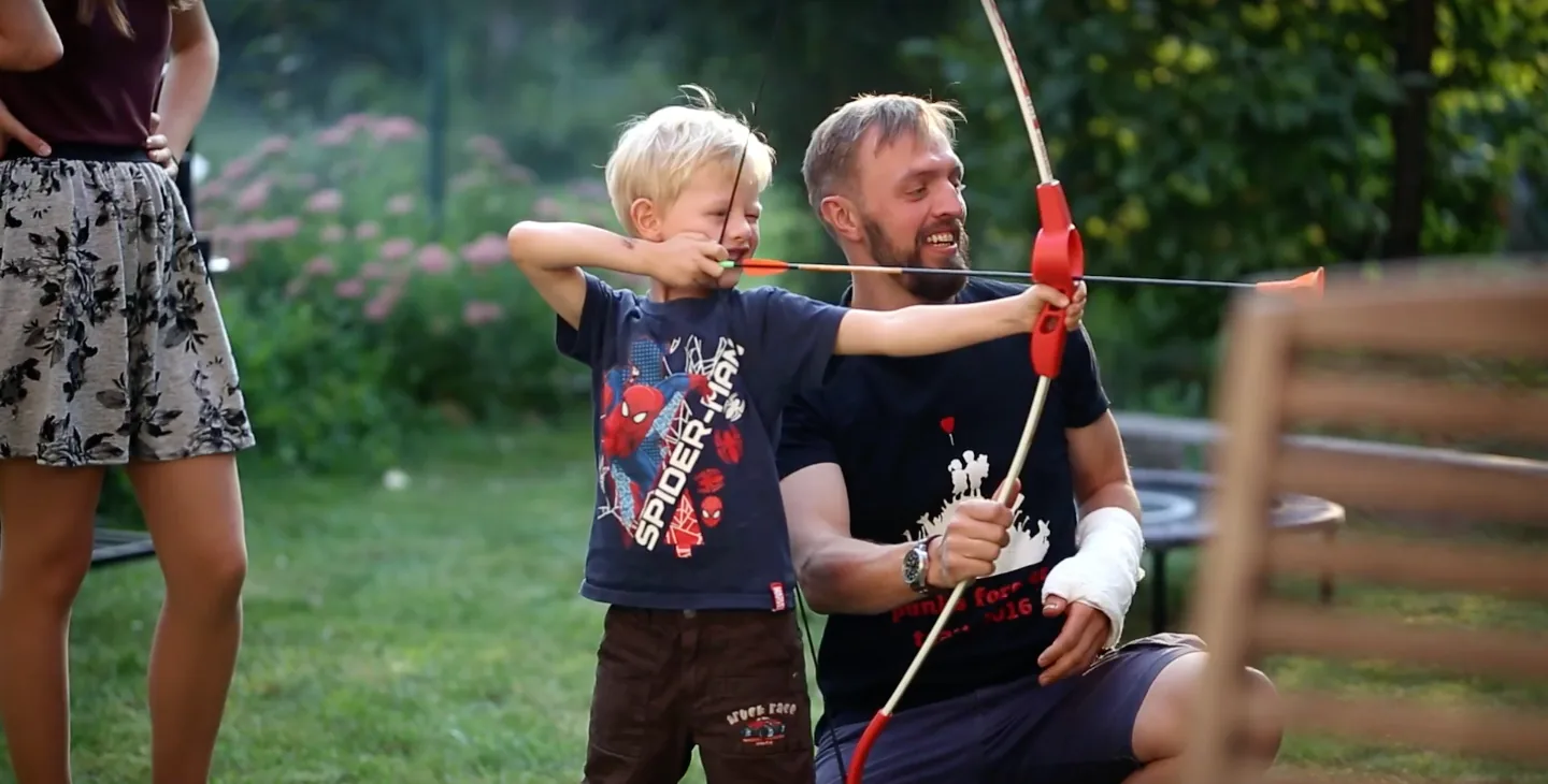 Ein Clowndoktor lernt mit einem Jungen Bogenschießen
