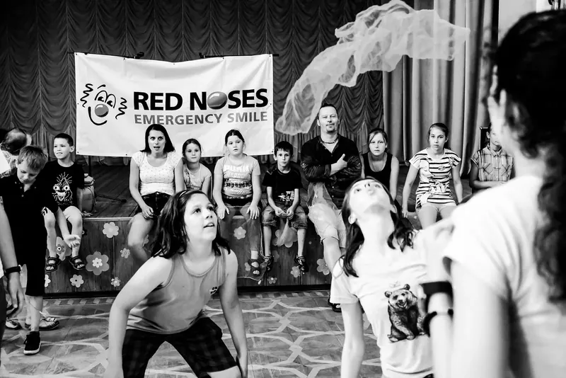 Kinder und Clowns vor dem ROTE-NASEN-Banner im Saal